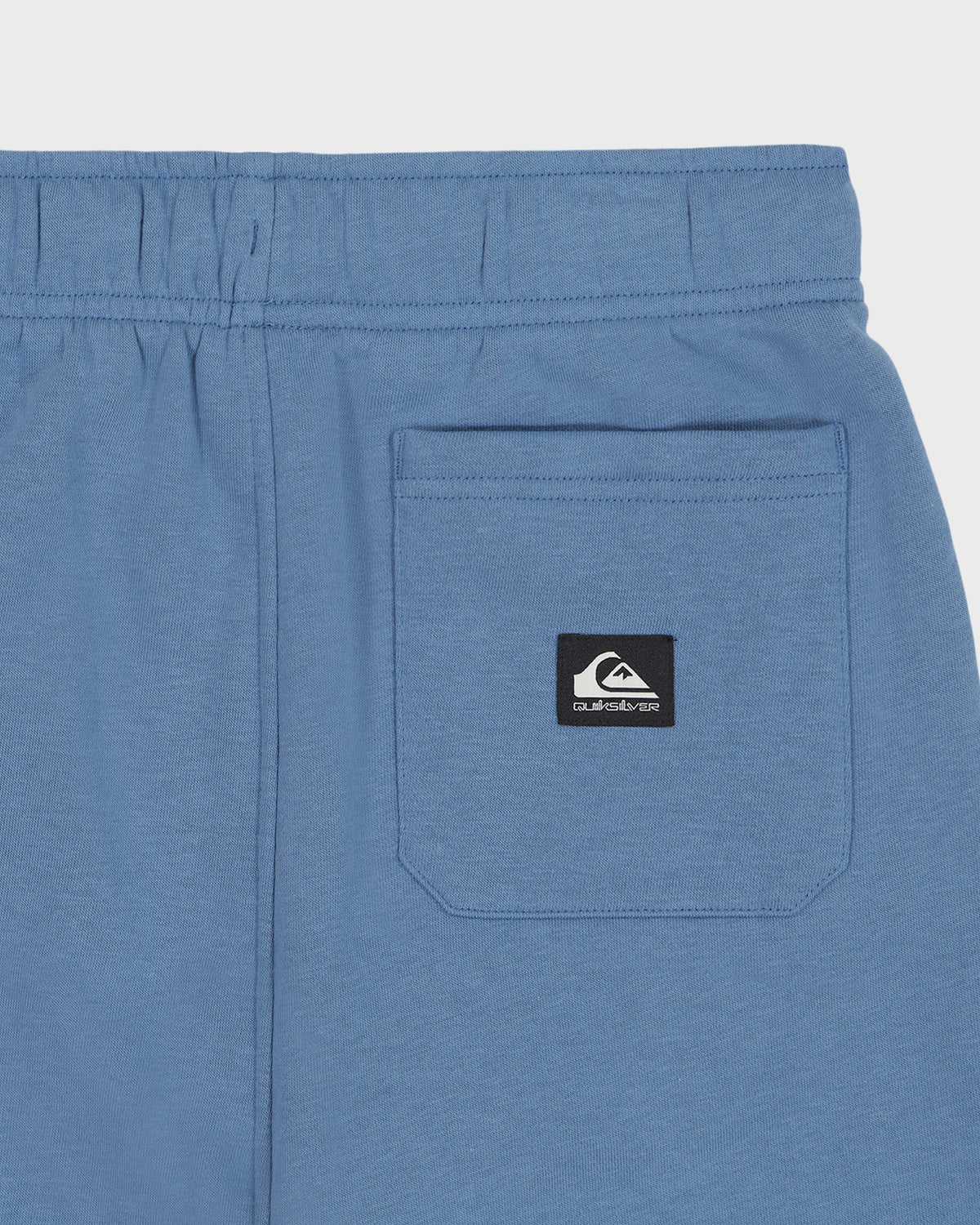 Blue shorts with a brand logo on the pocket against a light gray background
