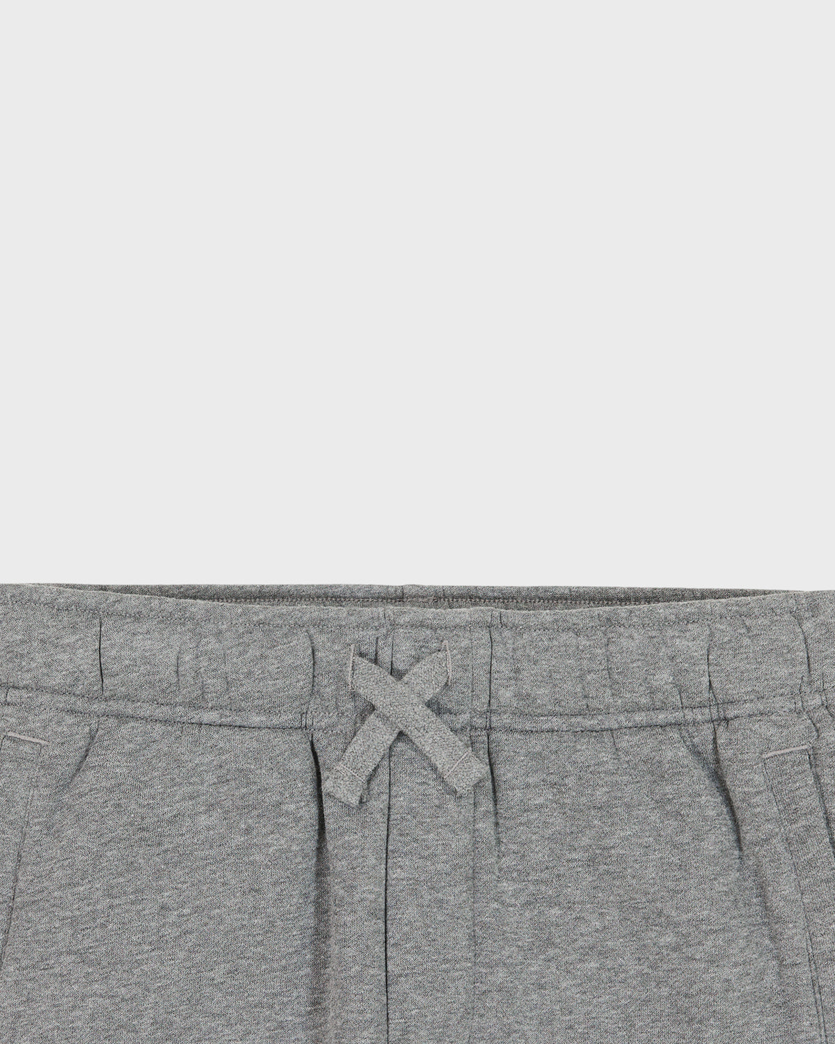Close-up of gray sweatpants with a drawstring on a light gray background