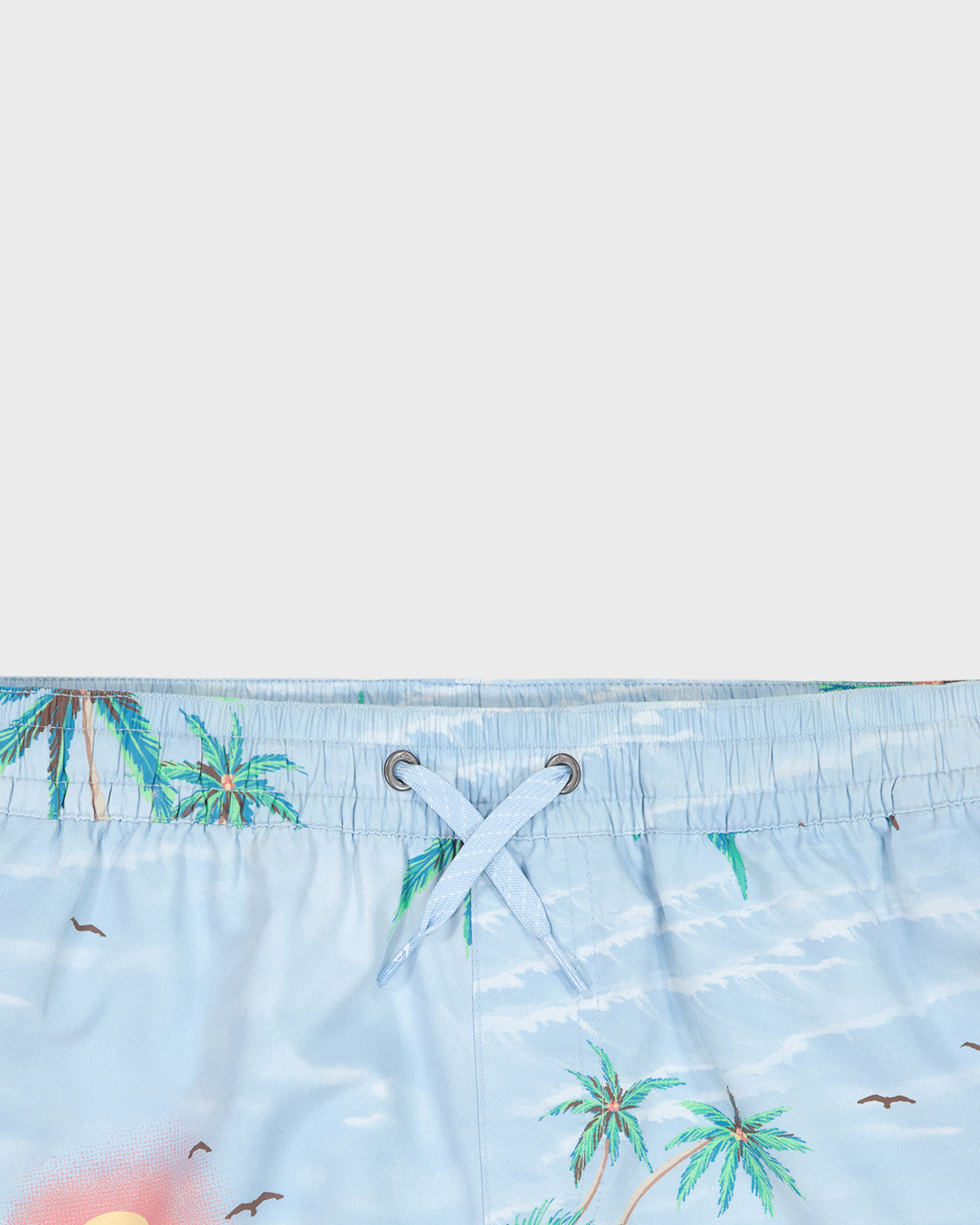 Close-up of a blue swimsuit with palm tree pattern on a white background